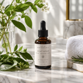 Botanical Night Serum in a dark amber dropper bottle on a marble vanity with fresh botanicals